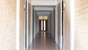 A long, narrow hallway with brick walls and white trim, leading to a door at the end. - Kilimanjaro Eco Hostel (Moshi)