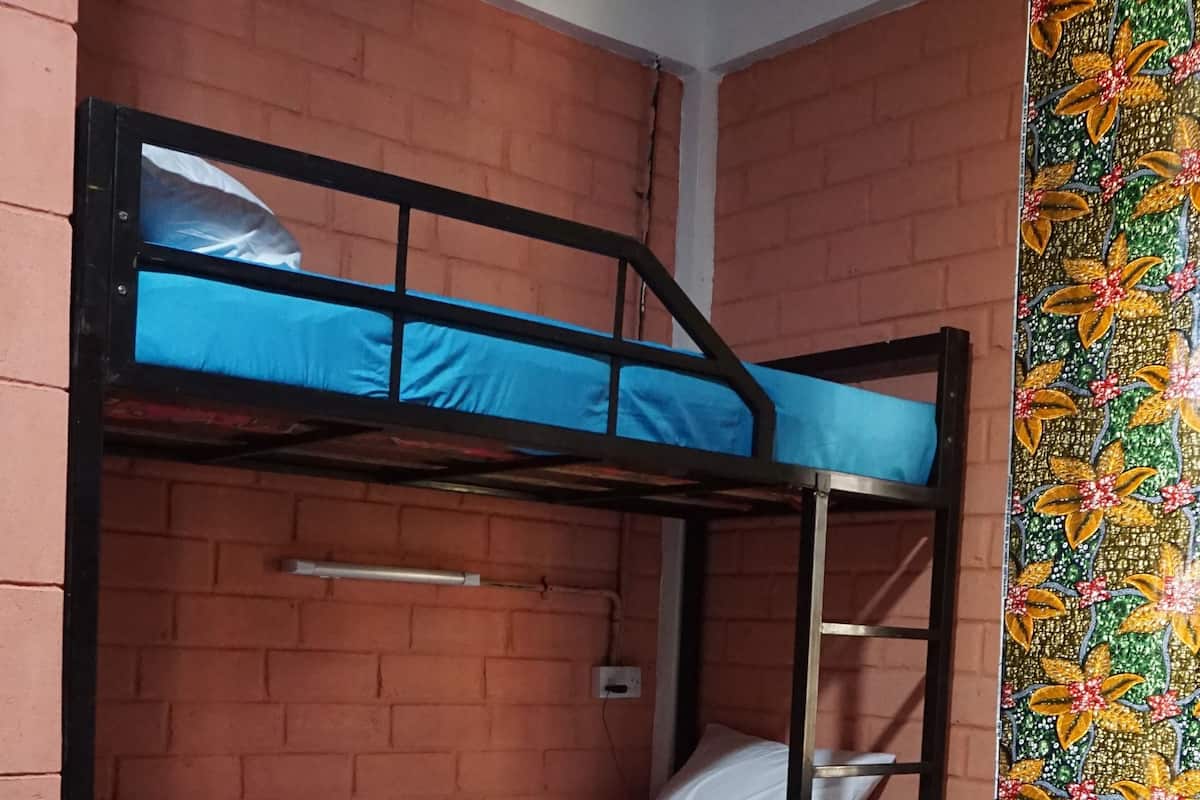 A dormitory room with two bunk beds, a table with a green tablecloth, and a vase with flowers.