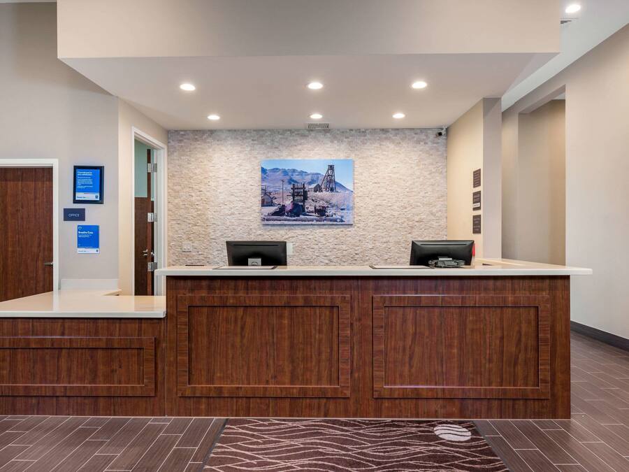 A reception desk with a stone wall backdrop, a framed picture, and a digital display.