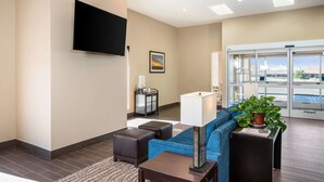 Een moderne lobby met een blauwe bank, een flatscreen televisie, een bijzettafeltje en een plant in pot.