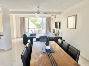 Un coin repas avec une table en bois, des chaises noires et une orchidée en pot.