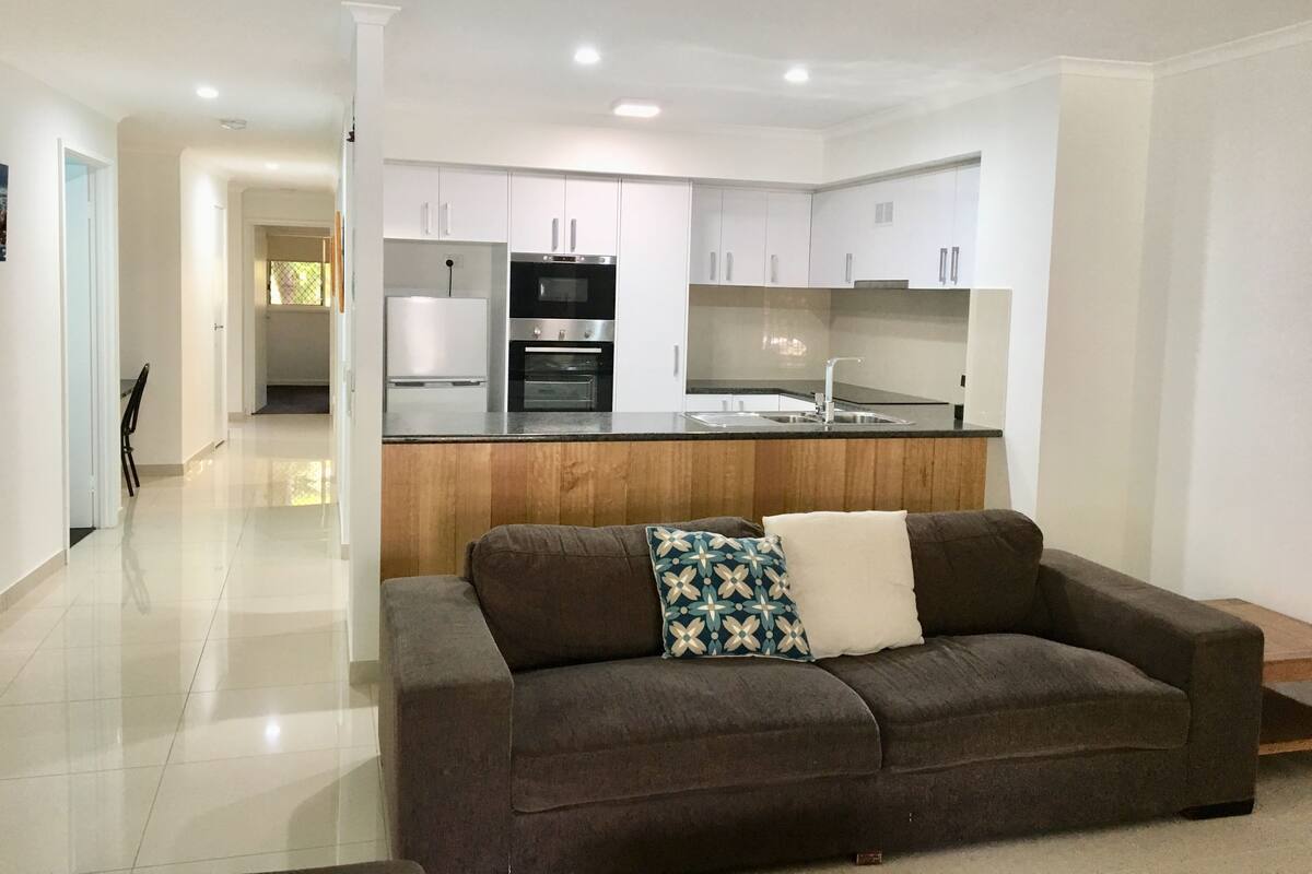A modern kitchen with white cabinets, a wooden countertop, and stainless steel appliances.