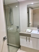 A modern bathroom with a glass-enclosed shower, a white sink, and a mirror above it.