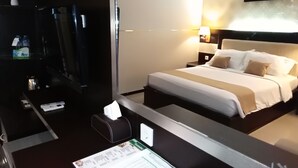 A hotel room with a bed, bedside tables, a desk with a lamp, a mirror, and a painting on the wall. - Zahra Syariah Hotel (Kendari)