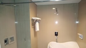 A modern bathroom with a freestanding bathtub, a towel rack, and a toilet. - Zahra Syariah Hotel (Kendari)