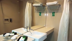 A modern bathroom with a large sink, two faucets, a mirror, and a shower curtain. - Zahra Syariah Hotel (Kendari)