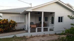 A single-story house with a covered porch, a small patio, and a garage. - Horizon House (Governor's Harbour)
