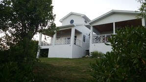 A two-story white house with a balcony, surrounded by greenery. - Horizon House (Governor's Harbour)