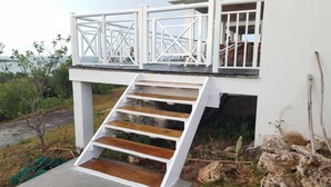 A white building with a wooden staircase leading to a balcony. - Horizon House (Governor's Harbour)