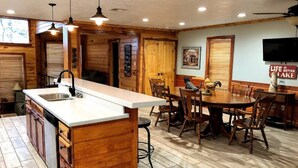 Une cuisine avec des meubles en bois, un plan de travail blanc et un coin repas comprenant des chaises et une table en bois.
