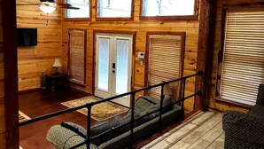 L’intérieur d’un chalet en bois, avec un escalier, un canapé, une lampe et un téléviseur.