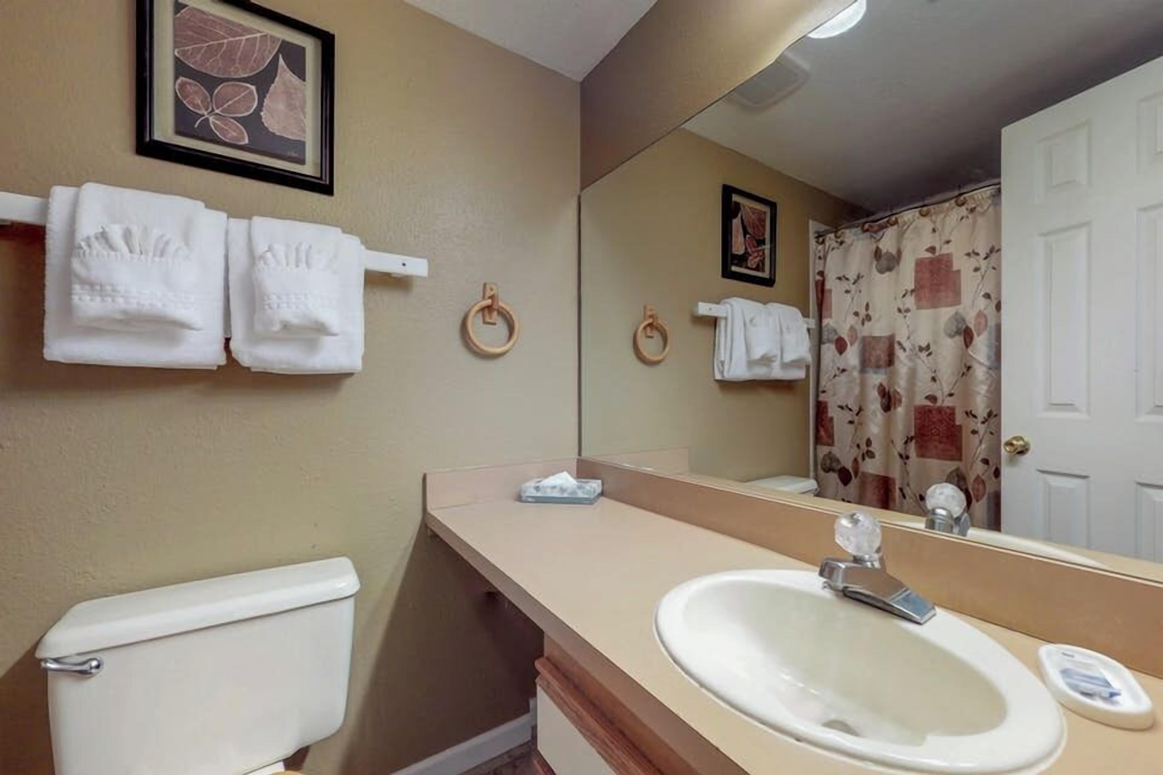 Un baño con inodoro, lavamanos y toallero.