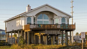 A two-story house with a balcony, elevated on stilts, and a 'No Vehicles on Beach' sign visible. - 1st row 4 bedroom 3 bath - Best views! (Galveston)