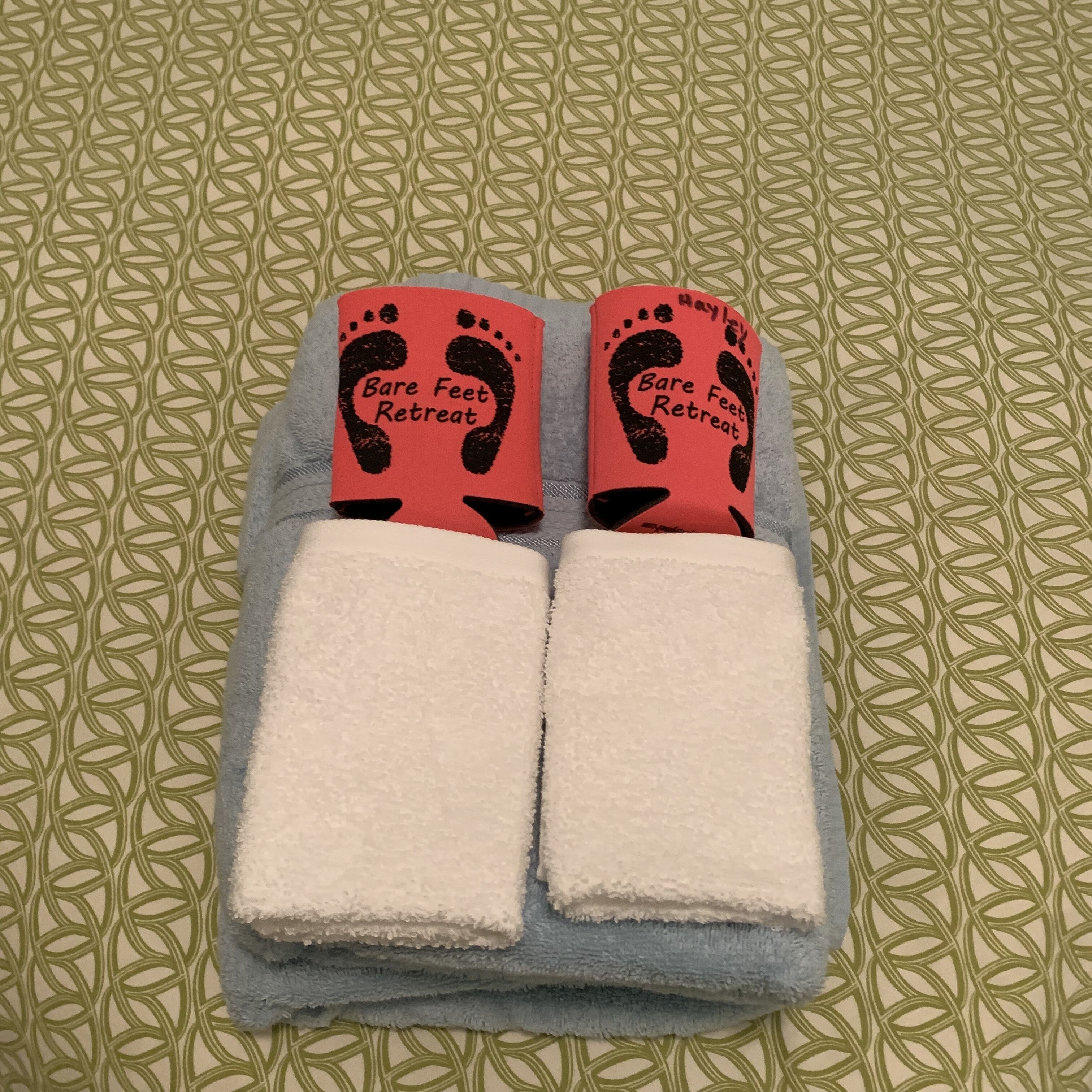 A pair of towels with a red and black design, placed on a patterned surface.