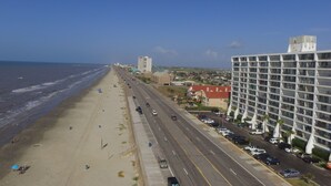 Una carretera costera con una playa a un lado y un hotel de diseño moderno al otro.