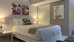 Un dormitorio moderno con una cama, dos lámparas de noche, una mesita de noche y un espejo grande.