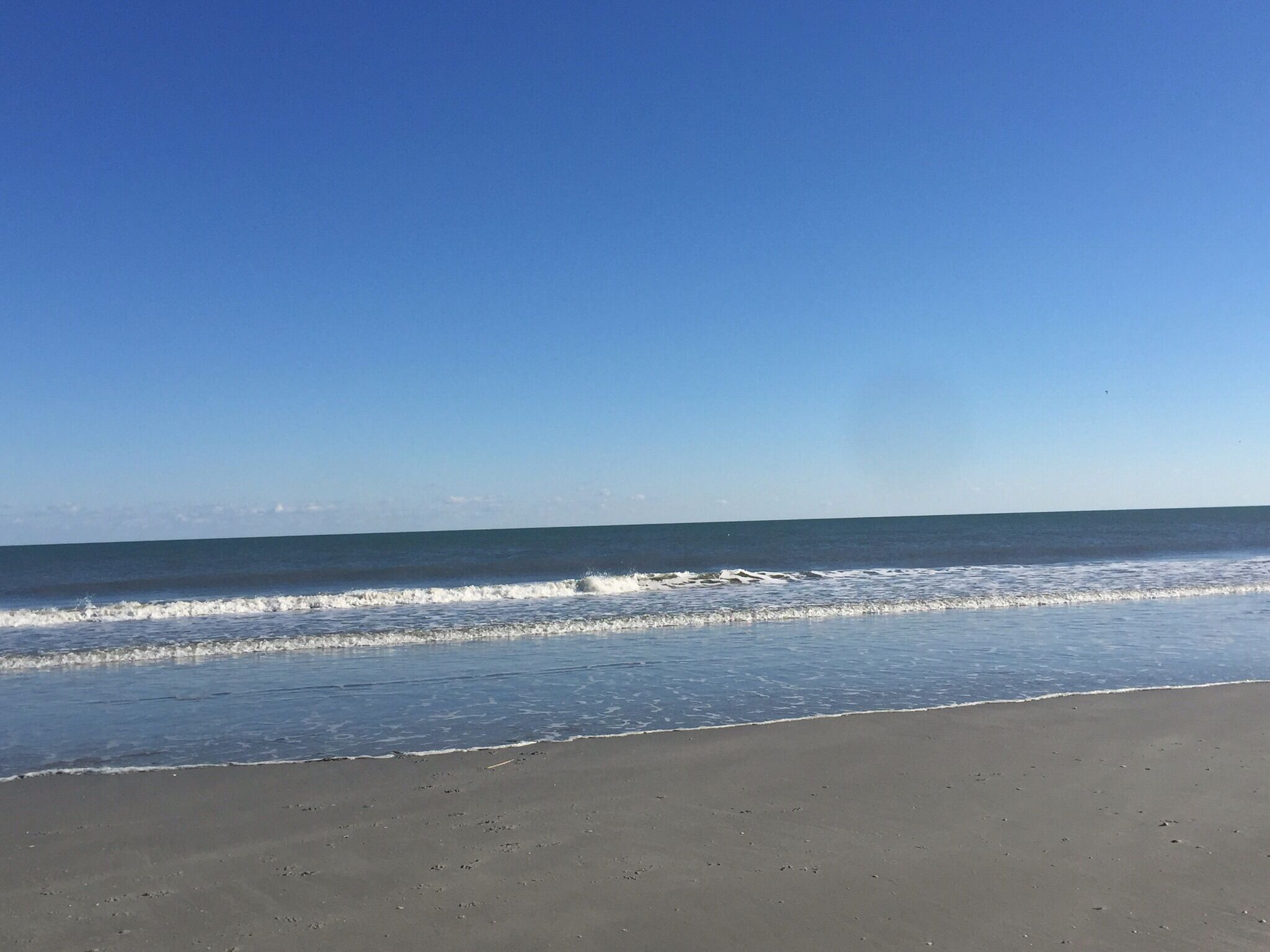 Une plage avec un ciel dégagé et une mer calme.