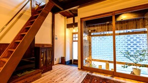 A wooden staircase leading to a room with a large window, a cabinet, and a plant. - Koume no Hanare (Kyoto)