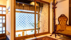 A room with a large sliding glass door leading to a balcony, a plush velvet armchair, and a wooden floor. - Koume no Hanare (Kyoto)