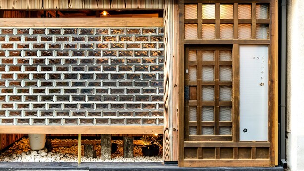 A traditional Japanese building with a wooden lattice door, a brick-patterned wall, and a wooden entrance. - Koume no Hanare (Kyoto)