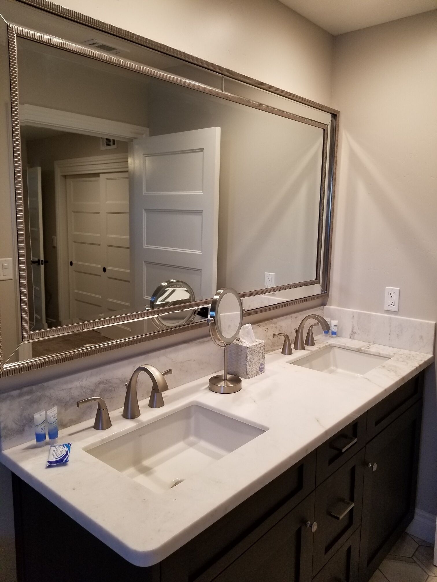 A bathroom with two sinks, a large mirror, and dark cabinets.