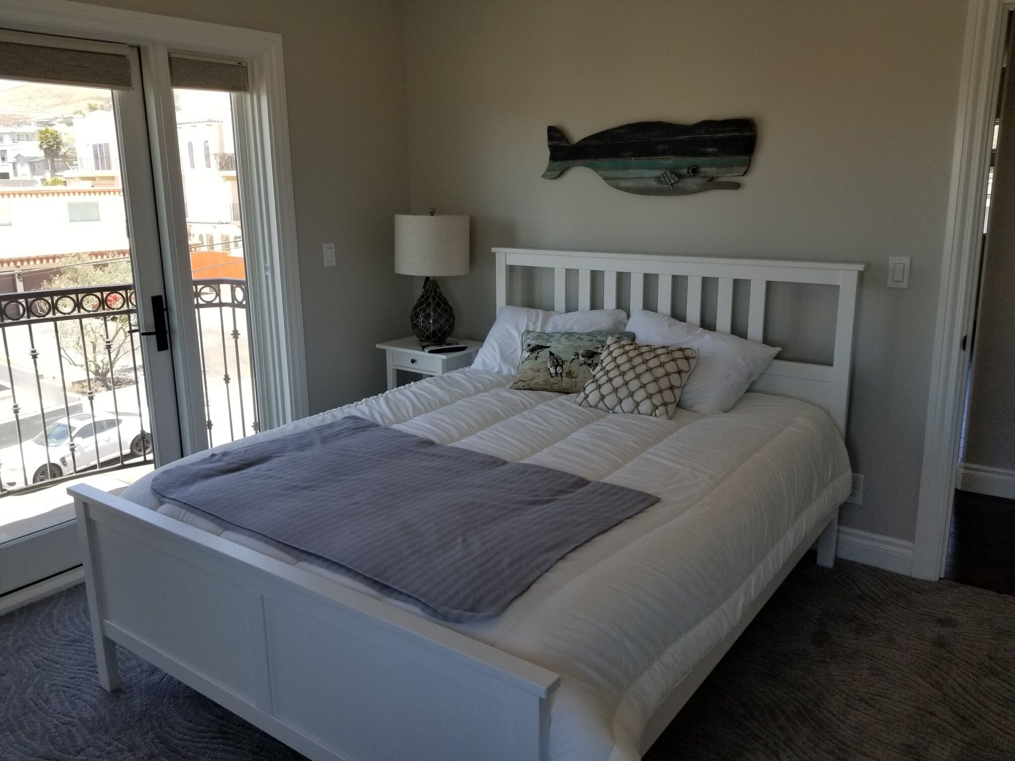 Un dormitorio con cama, mesita de noche, lámpara, decoración en la pared y vistas al exterior.
