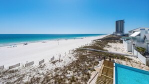 A beach view with a swimming pool, a tall building, and a sandy beach. - Broadmoor 304- Epic Vacations Start Here! Book Now! (Orange Beach)