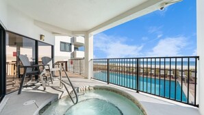 A balcony with a hot tub, pool, and chairs overlooking a beach. - Broadmoor 304- Epic Vacations Start Here! Book Now! (Orange Beach)