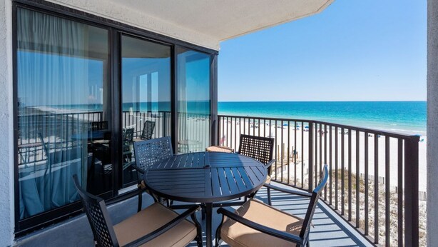 A balcony with a table and chairs, overlooking a beach. - Broadmoor 304- Epic Vacations Start Here! Book Now! (Orange Beach)