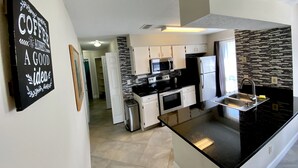 A modern kitchen with white cabinets, a black countertop, and a black backsplash. - Remodeled 3/2 condo minutes to Parks, shopping and entertainment (Kissimmee)