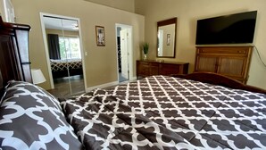 A bedroom with a large bed, a dresser, a television, and a door leading to another room. - Remodeled 3/2 condo minutes to Parks, shopping and entertainment (Kissimmee)