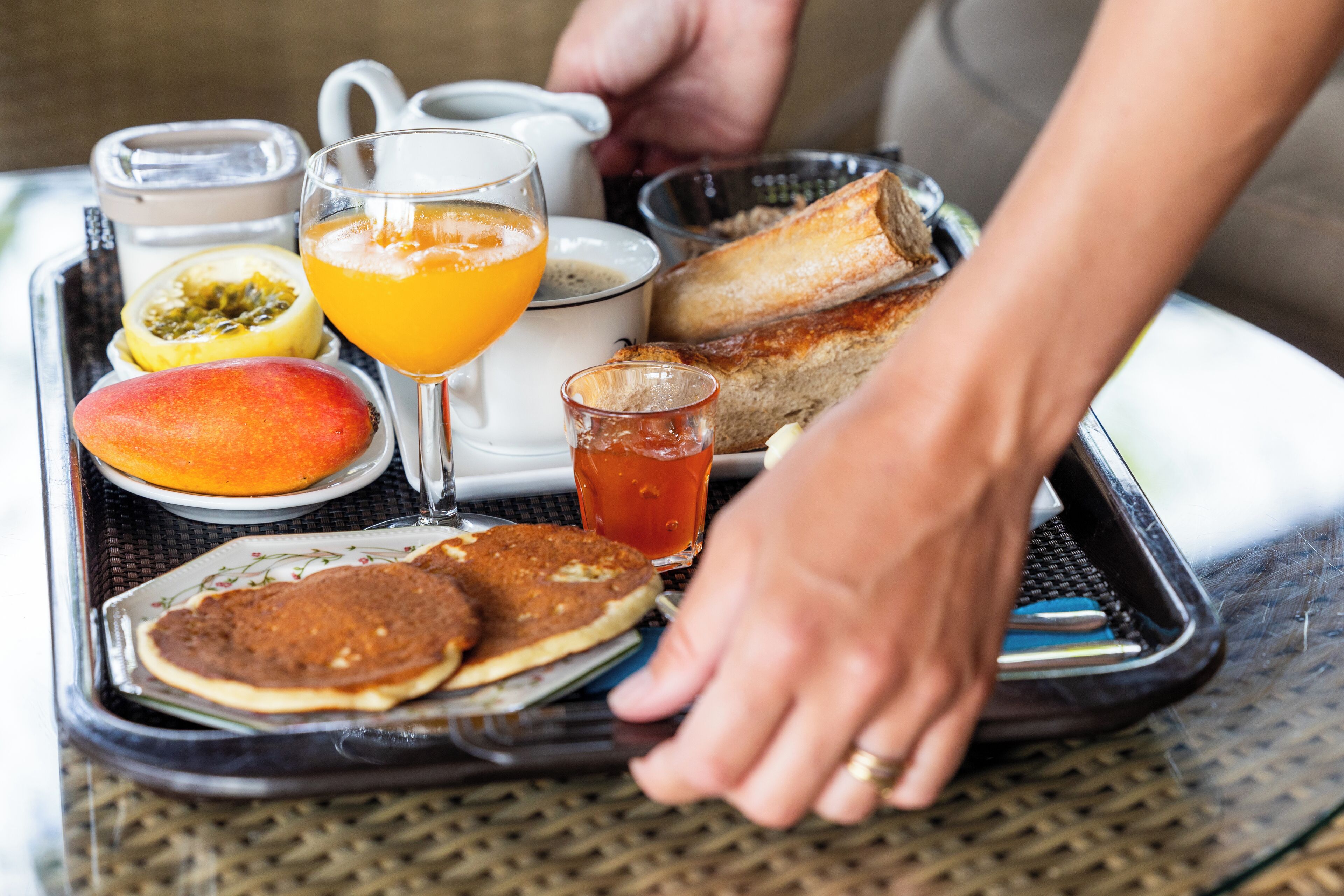 Bandeja de desayuno con panqueques, tostadas, fruta y bebidas.