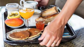 Bandeja de desayuno con panqueques, tostadas, fruta y bebidas.