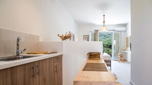 A modern kitchen with a wooden countertop, a built-in sink, and a view into a dining area with a long wooden table. - CASA BUGANVILLA 5 in Minia (Argostoli)