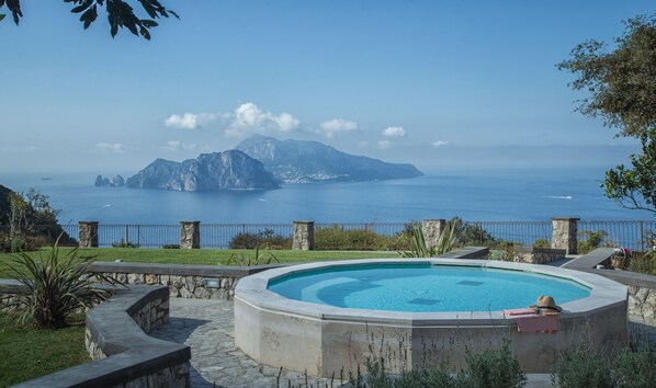 Piscina com vista para o mar e montanhas ao fundo.