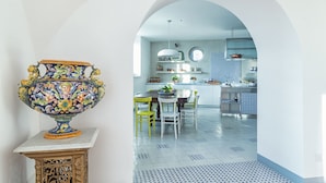 Una cucina con isola centrale, mobili bianchi e zoccolo paraschizzi a motivi blu e bianchi.