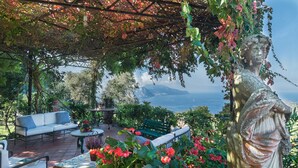 Patio giardino con una statua, zona relax e vista sul mare.