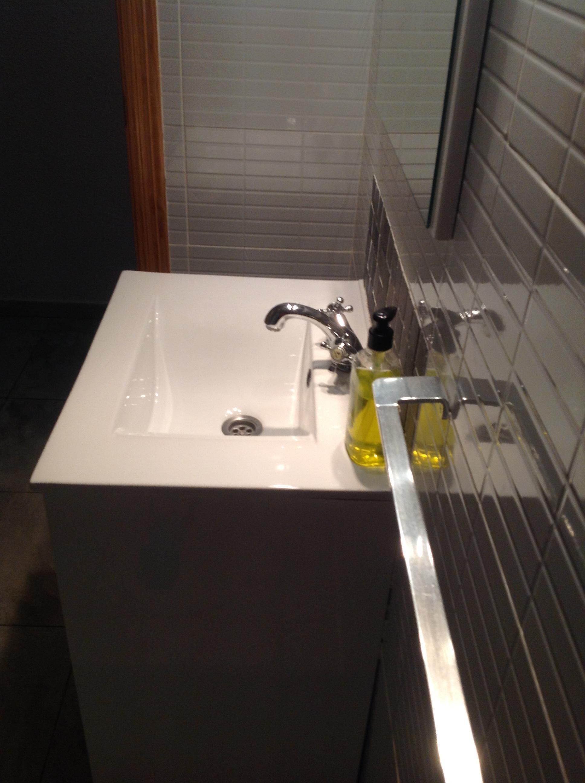Ein Badezimmer mit einem weißen Waschbecken, einem Spiegel und einer Flasche mit gelber Flüssigkeit.