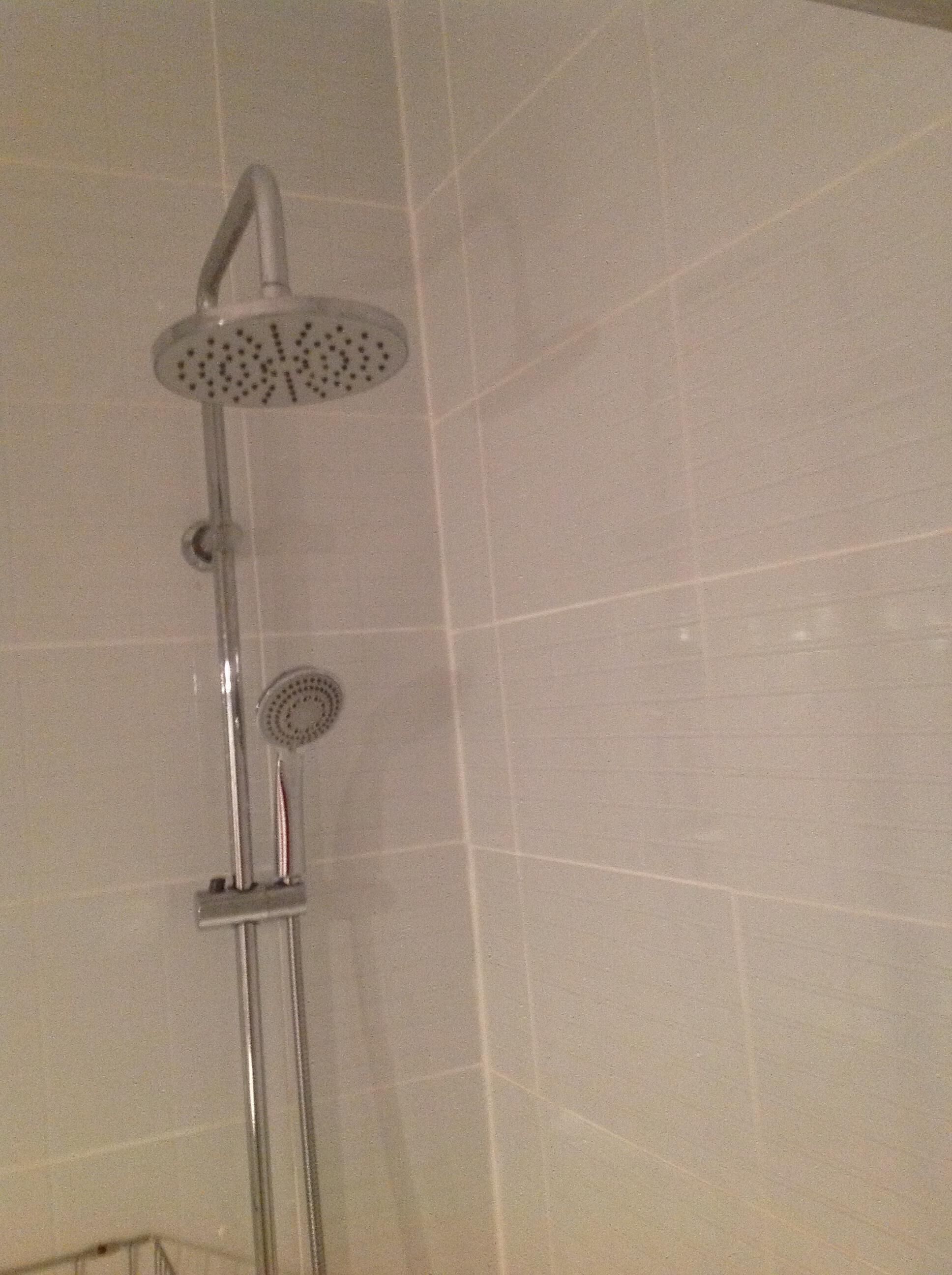 A shower with a handheld showerhead and a fixed wall-mounted showerhead.