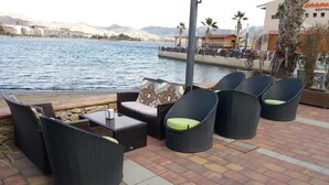 A patio with wicker furniture, a table, and a view of the sea and mountains. - Delightful family villa in secure gated community with large pool. (Puerto De Mazarrón)