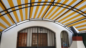 A building with a white facade, a curved archway, and a yellow-striped awning. - Delightful family villa in secure gated community with large pool. (Puerto De Mazarrón)