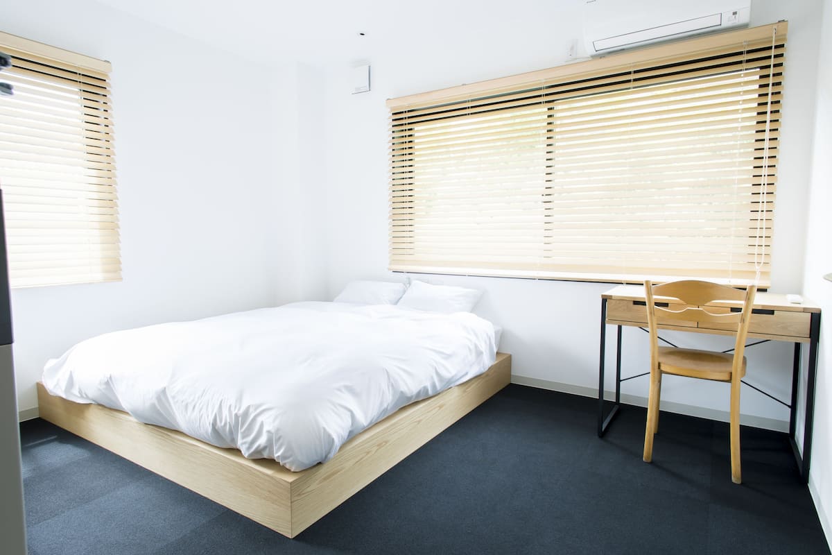 A bedroom with a bed, a desk, and a chair.