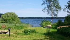 A grassy area with a bench and a lamp post, overlooking a body of water.