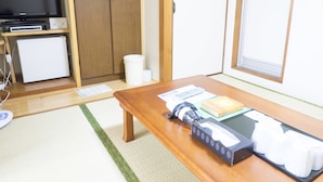 A compact room with a wooden table, a television, a small refrigerator, and a window with blinds. - Hikone Station Hotel (Hikone)
