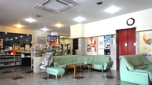 A lobby with a reception desk, a green sofa set, a wooden coffee table, and a clock on the wall. - Hikone Station Hotel (Hikone)