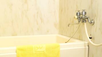 Un baño con bañera, una toalla amarilla y un grifo de ducha.