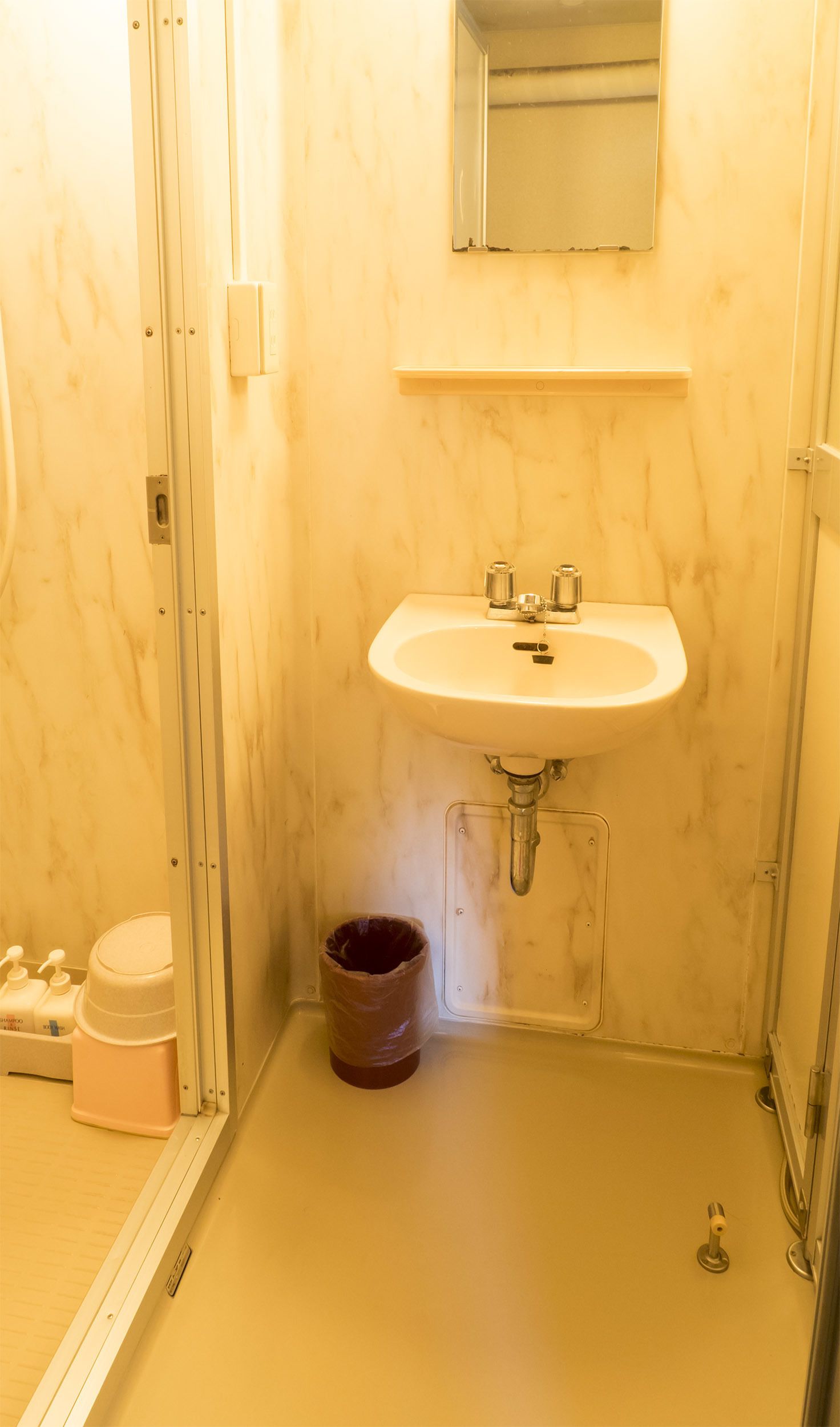A small bathroom with a sink, mirror, and shower.