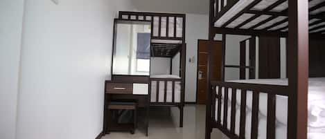 Une chambre avec des lits superposés, un bureau, un miroir et une armoire.