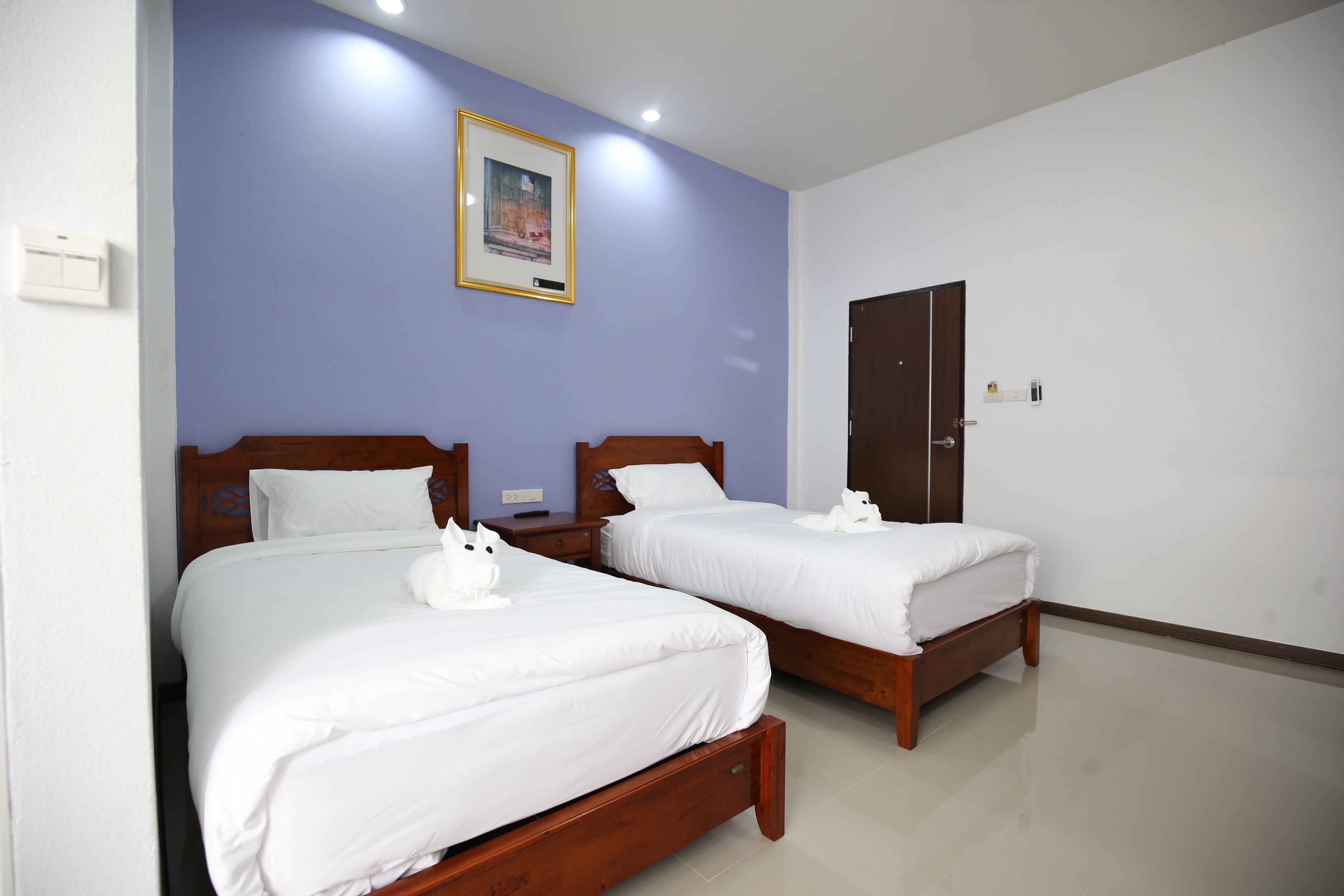 A hotel room with two beds, a wooden headboard, a framed picture on the wall, and a door.