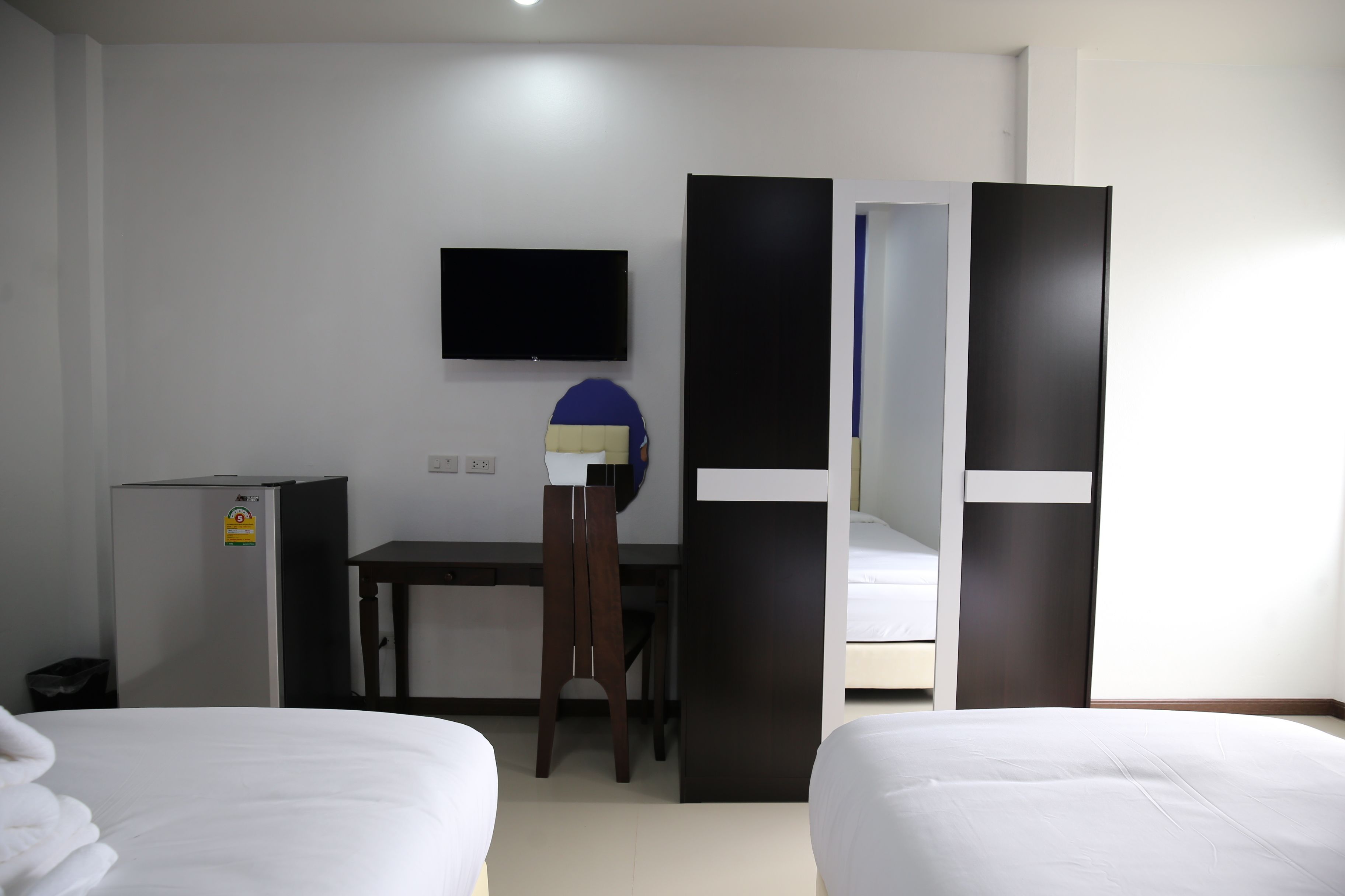 Una habitación de hotel con dos camas, un escritorio, una silla, un televisor y un armario.